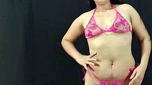 Beleza latina jovem e curvilínea exibe seus atributos em lingerie rosa e se prepara para uma sessão de fotos quente